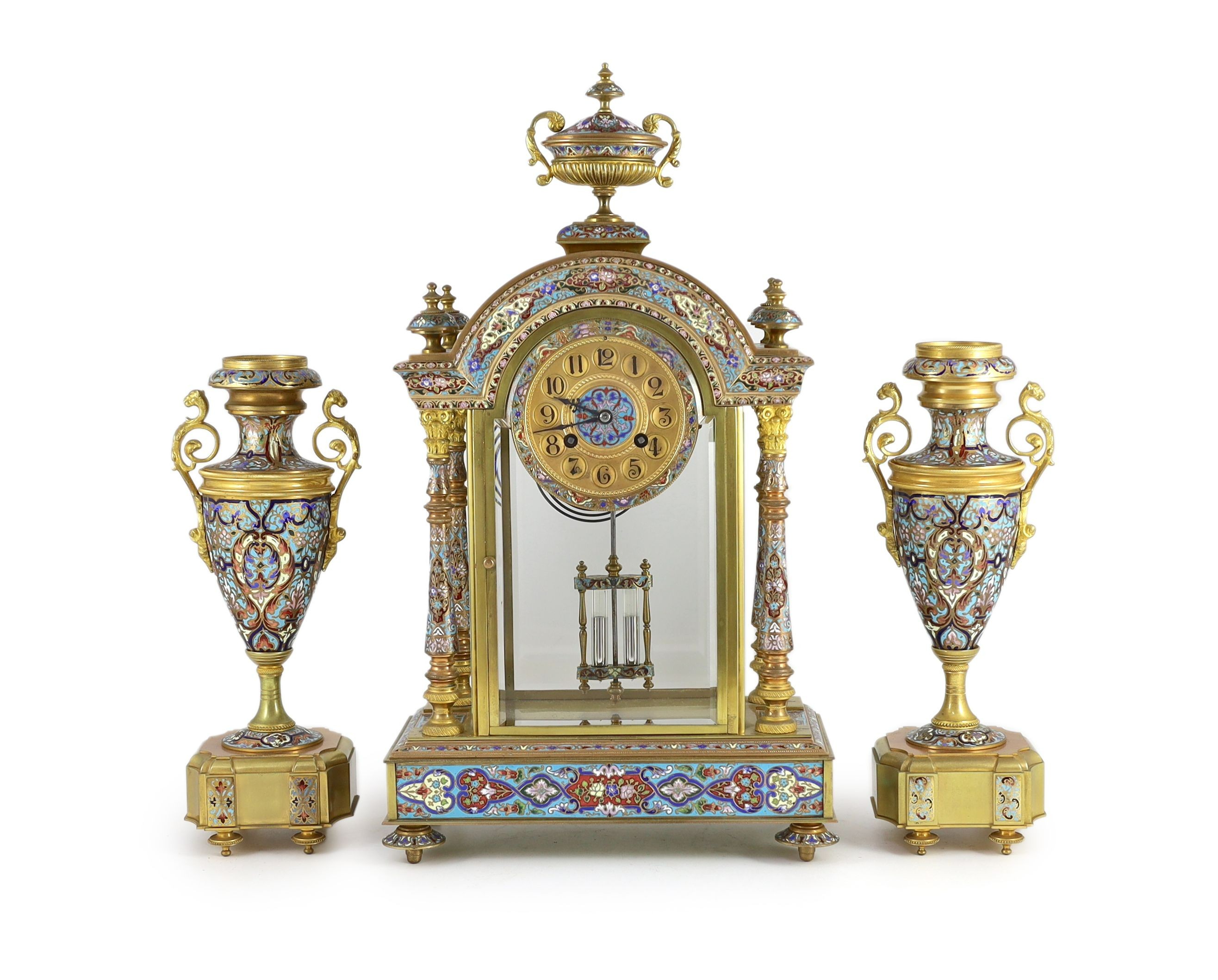 An early 20th century French ormolu and champleve enamel clock garniture, clock: height 50.5cm urns: height 32.5cm